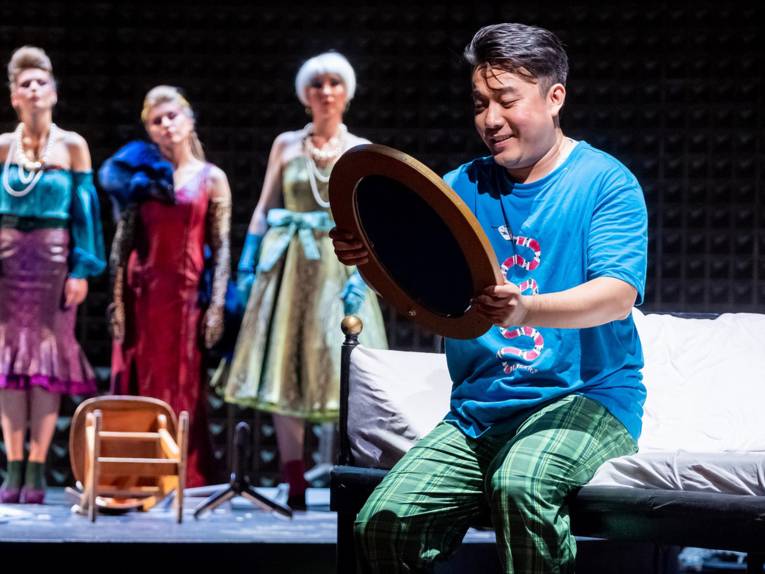 Bühnenszene: Mann schaut sich selbst lächelnd im Spiegel an